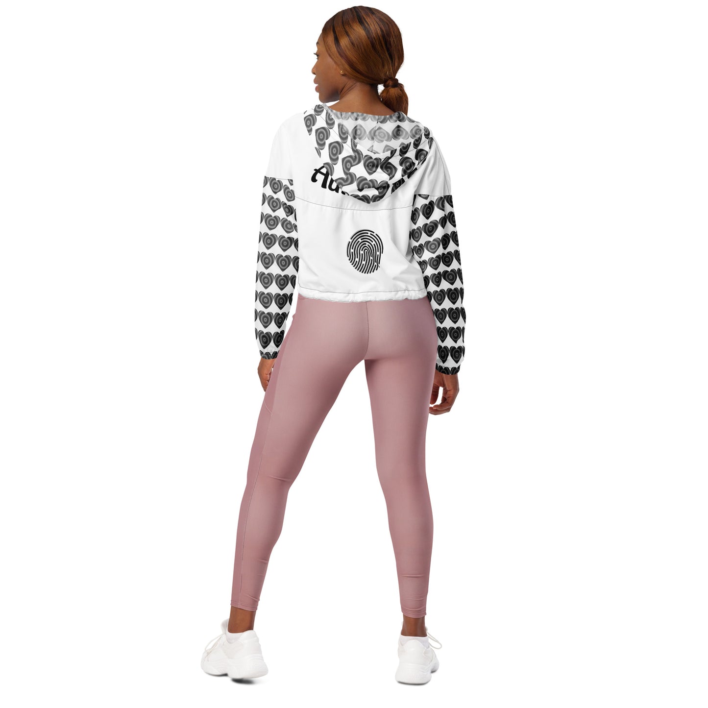 Woman with her back turned to the camera wearing a cropped windbreaker with side-slit pockets, breathable mesh lining, and adjustable drawcords. The windbreaker is predominantly white with a geometric pattern.