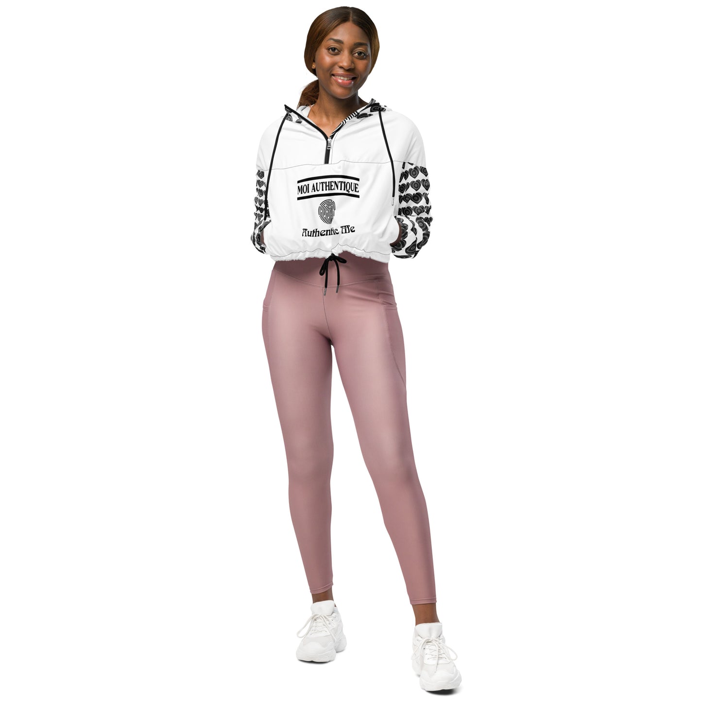 A woman wearing a cropped windbreaker with side-slit pockets, breathable mesh lining, and adjustable drawcords. The windbreaker is predominantly white with a geometric pattern.