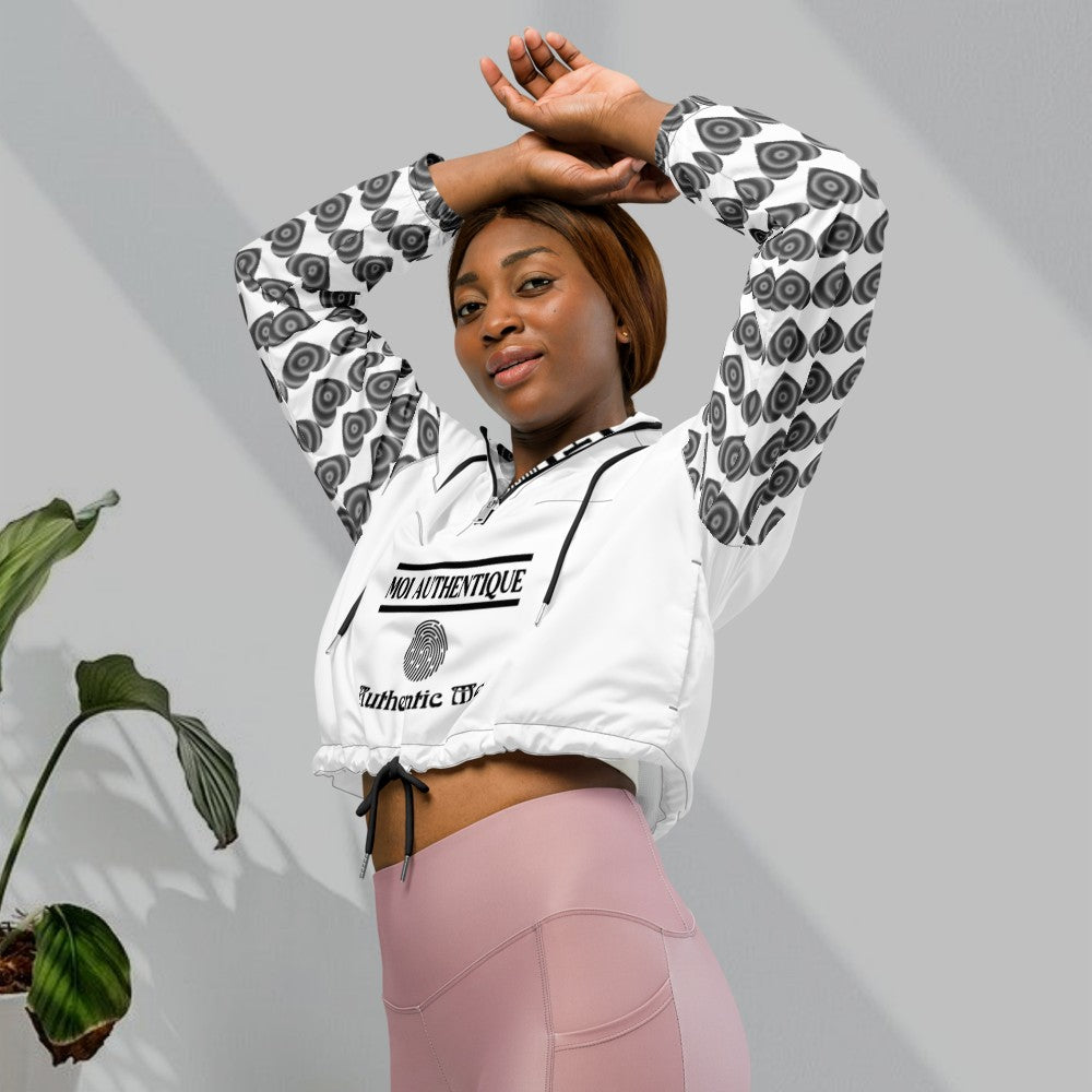 A woman wearing a cropped windbreaker with side-slit pockets, breathable mesh lining, and adjustable drawcords. The windbreaker is predominantly white with a geometric pattern.