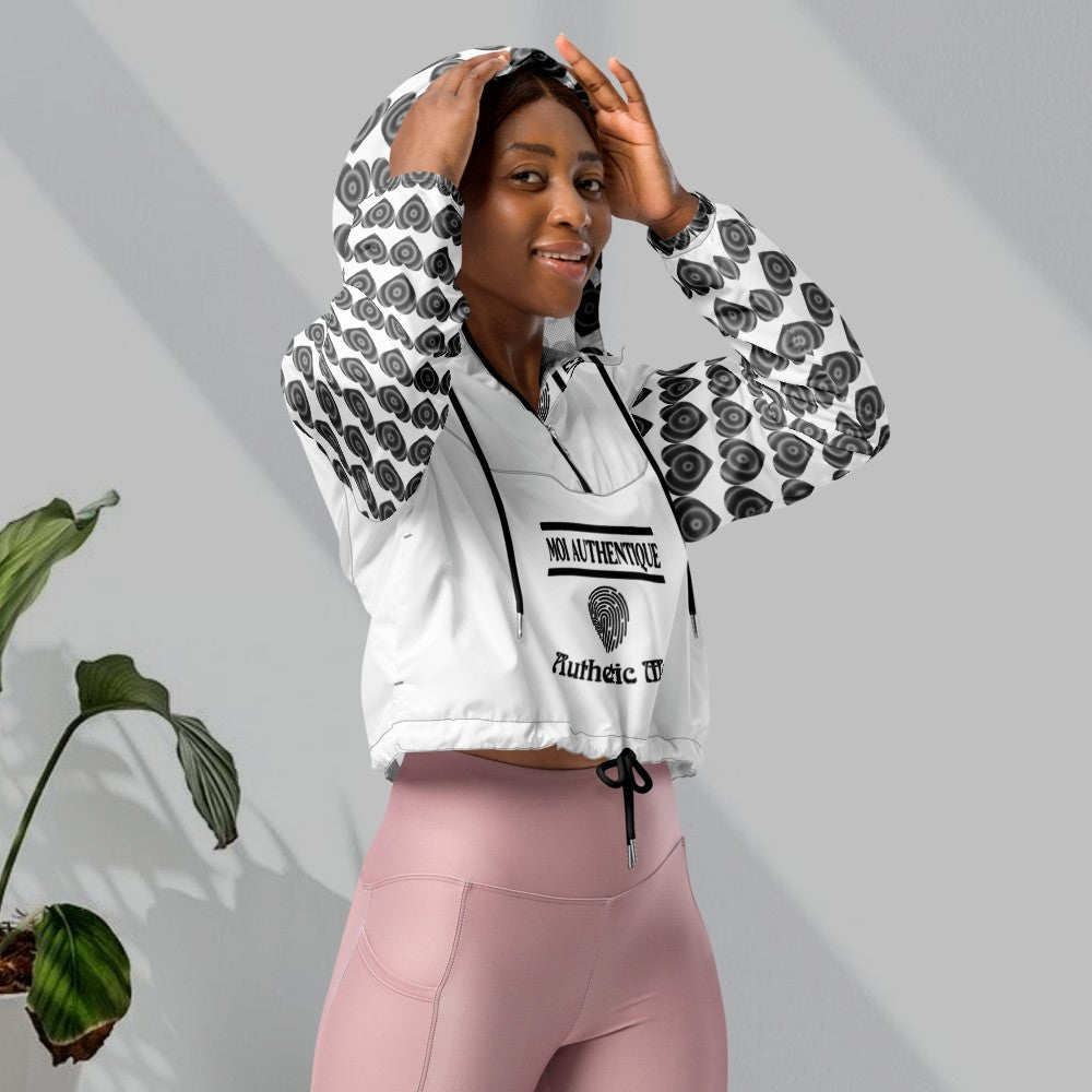 A woman wearing a cropped windbreaker with side-slit pockets, breathable mesh lining, and adjustable drawcords. The windbreaker is predominantly white with a geometric pattern.