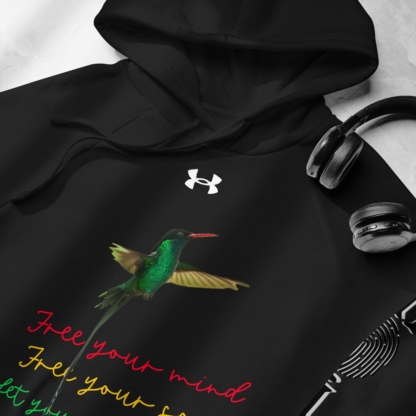 Moi Authentique product display showing a black Under Armour hoodie with multicoloured text and graphics, a front pouch pocket, and ribbed cuffs.