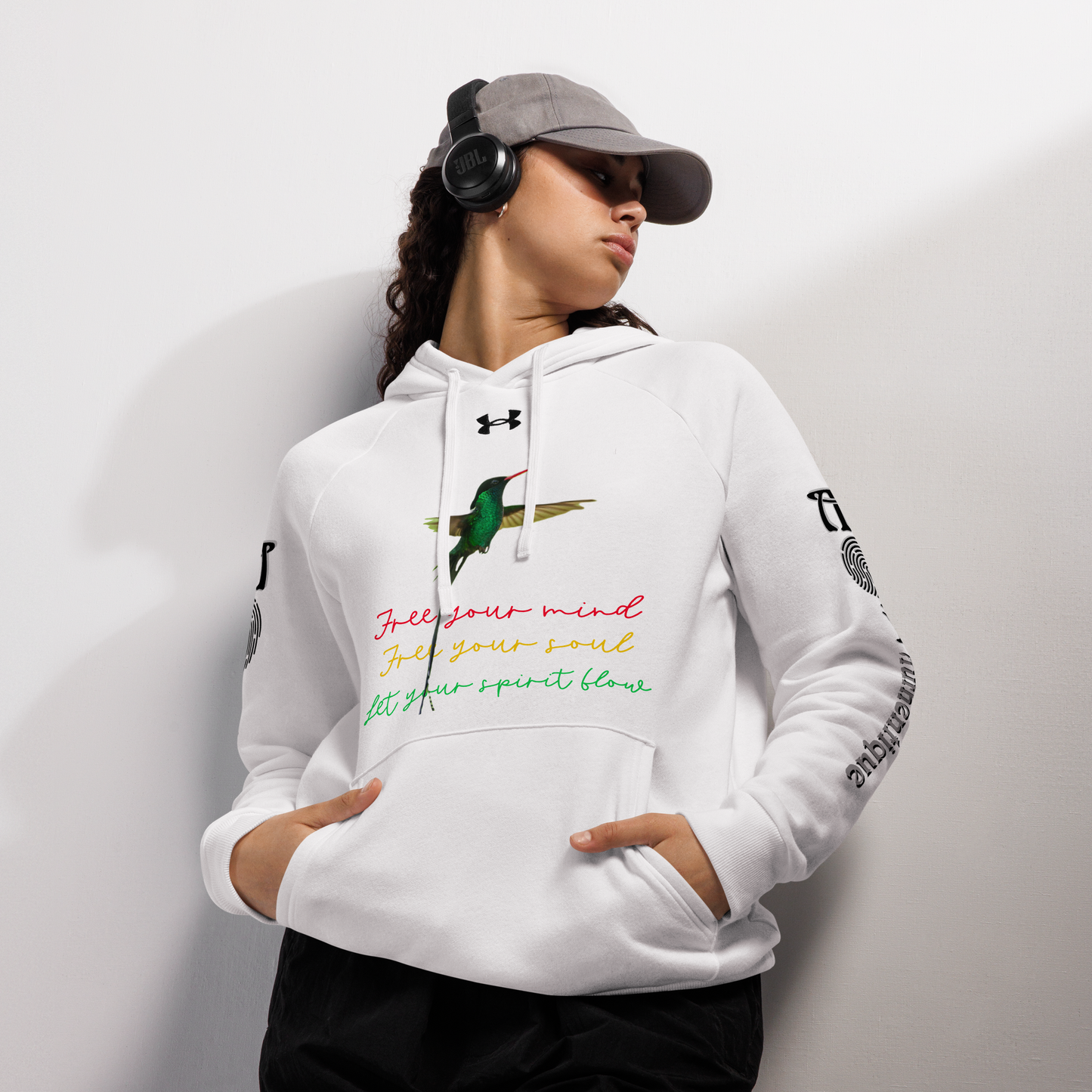 A person wearing a white Under Armour hoodie with multicoloured text and graphics, a front pouch pocket, and ribbed cuffs.