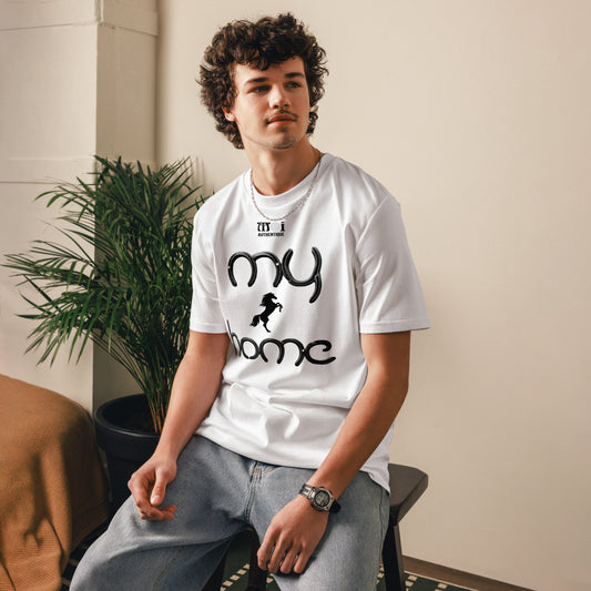Man sitting on a stool wearing a white t-shirt with a small image of a horse with writing saying my home